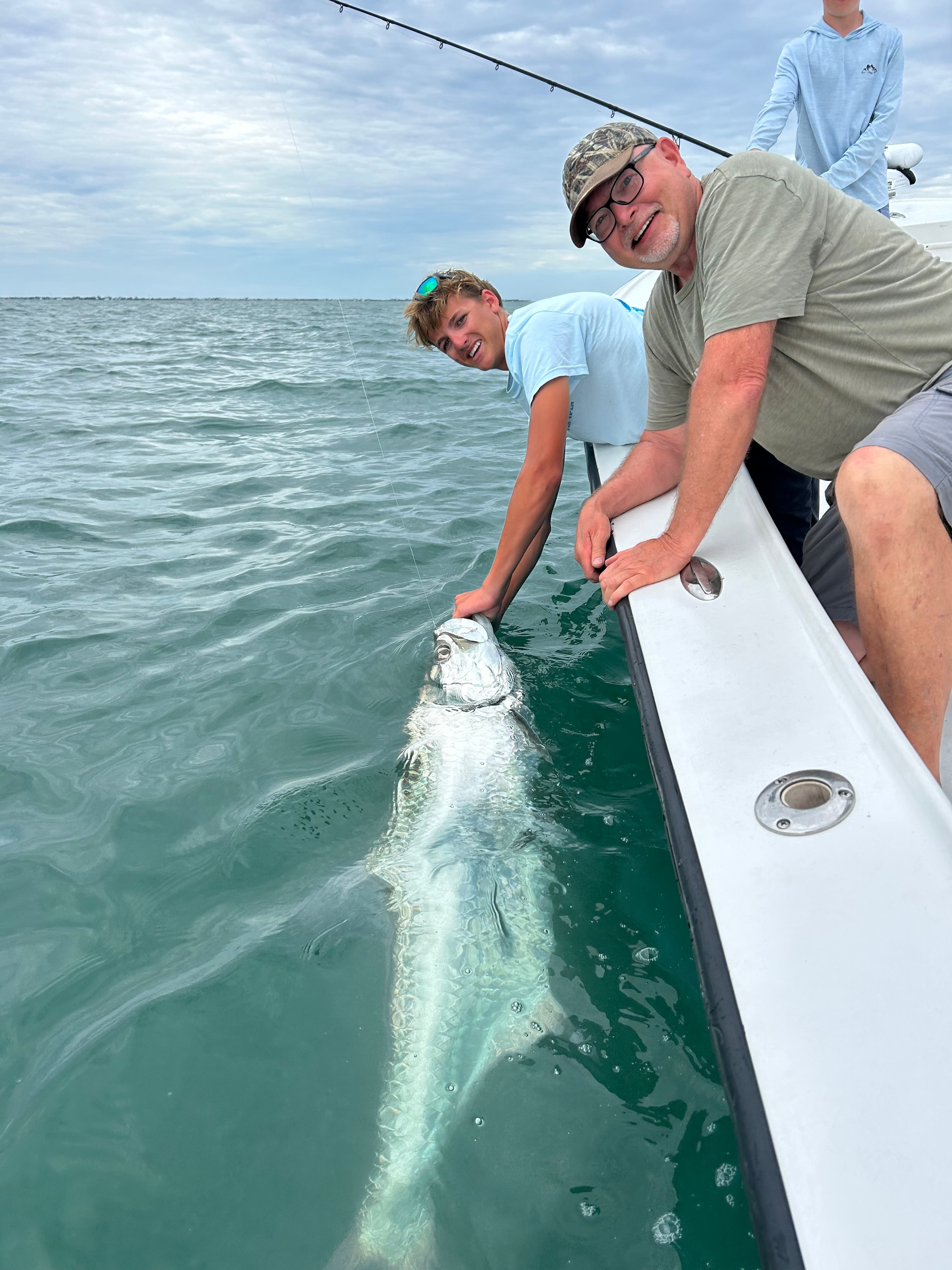 Father and son releasing a tarpon at the side of the boat